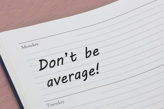 A Dont be average motivated concept diary reminder open on a desk