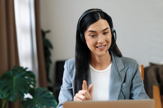 Female call center operator or customer service helpdesk staff working on workspace while talking on the headset to provide assistance for customer. Professional modern business service. Blithe