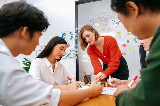 Creative happy business team brainstorming and sharing idea by using mind map and graphic graph while young beautiful project manager pointing at important point at business meeting. Immaculate.