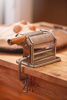 Cooking, dough and pasta maker in kitchen on table, counter and wooden board for cuisine. Food, baking and culinary tool, machine or utensil for flour, ingredients and eggs for homemade noodles.