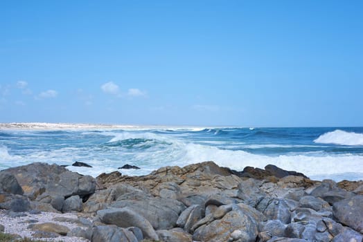 Ocean, waves and rocks on coast of beach in Malaysia for outdoor travel in summer for vacation or holiday. Sea, stone and blue sky with landscape for wallpaper or background, water and nature