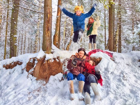 Joyful family ethnic dress with shawls and earflap hats in winter forest in carnival Maslenitsa in Russia. Tourists in Shrovetide in spring. Mother, father, son, daughter having fun in the snow