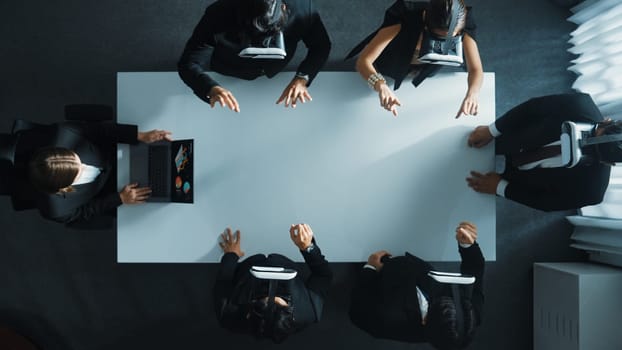 Top down aerial view of professional business team wear vr headset to enter virtual world while sitting and using hand gestures to manipulate the data from the manager laptop. Technology. Directorate.