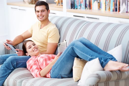 Couple, home and smile on sofa to relax with tablet for social media, networking and entertainment. Portrait, couch and living room with reading book or novel for fiction, story and knowledge.