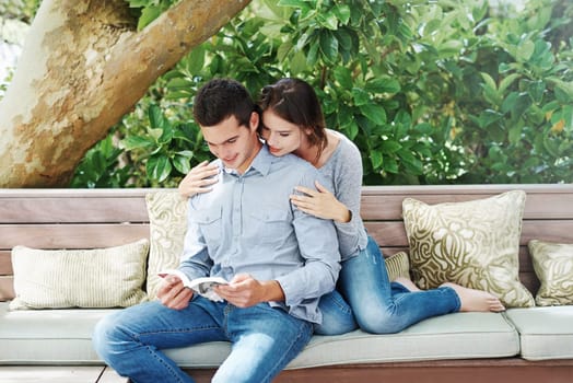 Couple, reading and book on couch at house to relax or bond with fiction or information for knowledge development. Romantic, man and woman on bench for support or growth for freedom or peace together.