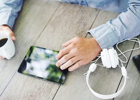 Table, coffee and hand with typing on tablet for communication, social media or online search. High angle, morning and man with digital technology on desk for text message, networking or connectivity.