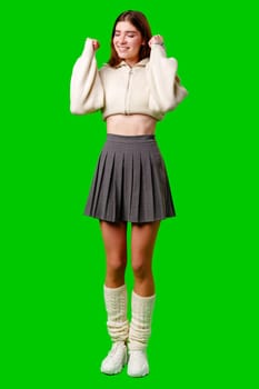 A woman wearing a skirt and sweater is standing in a posed position, looking directly at the camera. She appears confident and stylish as she poses for the photograph.