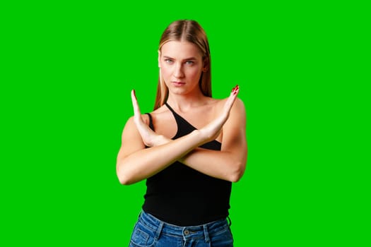 Young Woman Making Stop Sign Gesture on green background in studio