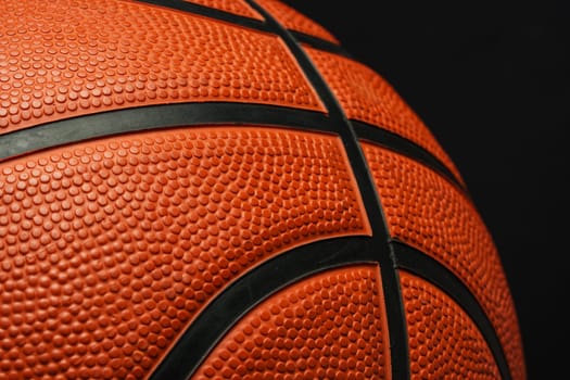 This close-up shot showcases a basketball resting on a black background. The textured surface of the basketball contrasts sharply with the dark backdrop, emphasizing its details.