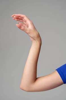 Female hand sign against gray background in studio close up