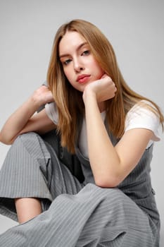 Young Woman in a Gray Suit Sitting on the Floor in Studio portrait