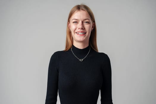 Smiling Woman in Black Top against gray background in studio