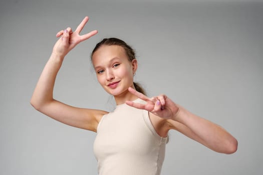 Young Girl Making a Peace Sign on gray background in studio