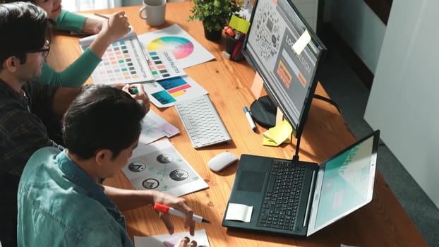 Top down view of smart designer helping manager choosing color from colored palettes. Aerial view of businessman working together and planning together while looking at logo from laptop. Symposium.