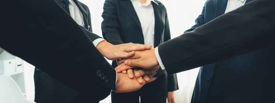 Office worker team stacking hand together symbolize successful group of business partnership and strong collective unity teamwork in community workplace in panoramic banner. Shrewd