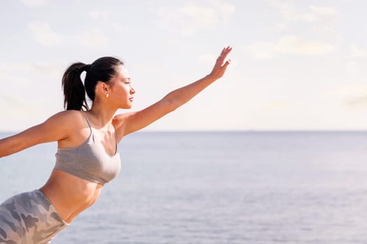 young asian woman in sportswear exercising on the beach with yoga poses, concept of mental relaxation and healthy lifestyle, copy space for text