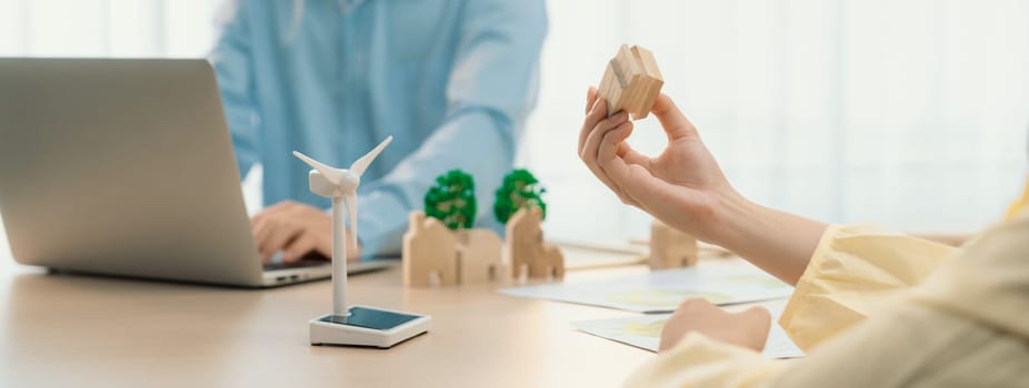 Businesswoman decides to Invest in green business. Skilled architects plan to build a eco house by using renewable energy at table with environmental document scatter around. Close up. Delineation.