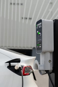 EV electric car recharge battery at parking lot in city commercial zone or mall. Alternative clean energy technology for rechargeable automobile for sustainable and eco friendly travel. Expedient