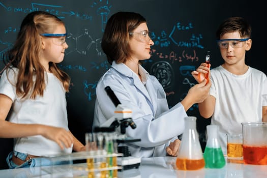 Teacher in support and watch student in laboratory they wear safety glasses, stand and experiment about science of chemistry in STEM class. Student funny do experiment with liquid in tube. Erudition.