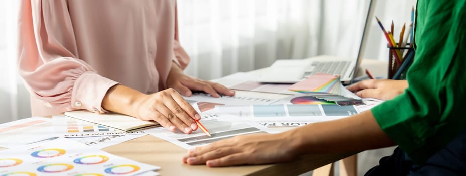 Cropped image of professional interior designers discuss and brainstorm main theme color in project on meeting table with color palette scatter around. Creative interior design concept. Variegated.