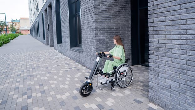 A woman in a wheelchair with an assistive device for manual control. Electric handbike