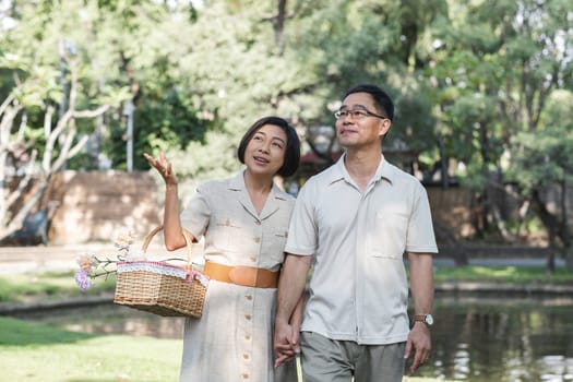 A retired couple walks outside together in the park on a relaxing vacation..