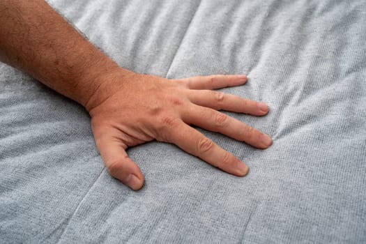 The man checks the quality and softness of the new mattress he will buy by pressing it with his hand