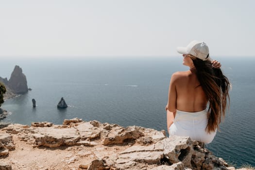 Woman travel sea. Young Happy woman in a long red dress posing on a beach near the sea on background of volcanic rocks, like in Iceland, sharing travel adventure journey