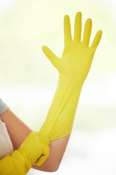 Person, hands and cleaner with gloves for cleaning, housekeeping or disinfection at home. Yellow closeup of maid or domestic worker getting ready with protection for health and safety from bacteria.