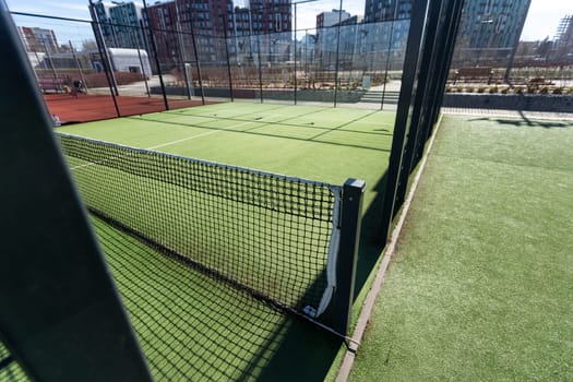 Landscaped areas of a residential development with a tennis court with high Plexiglas and metal fences. High quality photo
