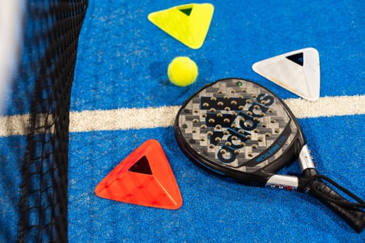 Kyiv, Ukraine, April 18, 2024. Black professional paddle tennis racket and ball with natural lighting on blue background. Horizontal sport theme poster, greeting cards, headers, website and app. High quality photo