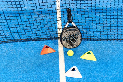 Kyiv, Ukraine, April 18, 2024. Black professional paddle tennis racket and ball with natural lighting on blue background. Horizontal sport theme poster, greeting cards, headers, website and app. High quality photo