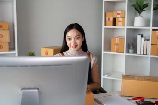 Young business woman asian working online ecommerce shopping at her shop. Young woman sell prepare parcel box of product for deliver to customer. Online selling.