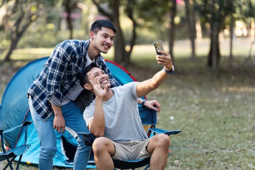 LGBTQIA Gay couple camping together in woods for holidays and relax together at the weekend.