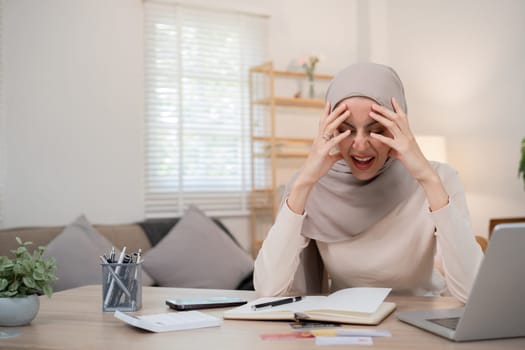 A young Muslim business woman is stressed and has a headache from miscalculating business numbers and problems with company expenses..