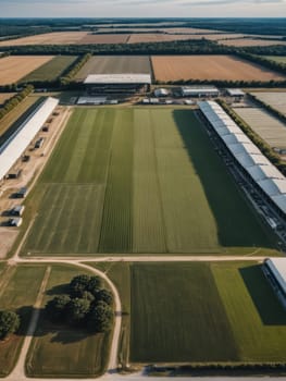 Aerial view of a modern farm with green fields and large storage buildings, showcasing agricultural development