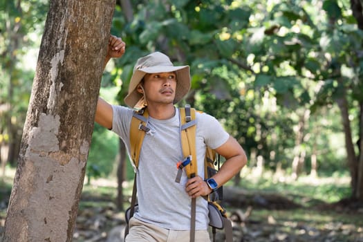 man with backpack walk along forest path while hiking and camping on the weekend.