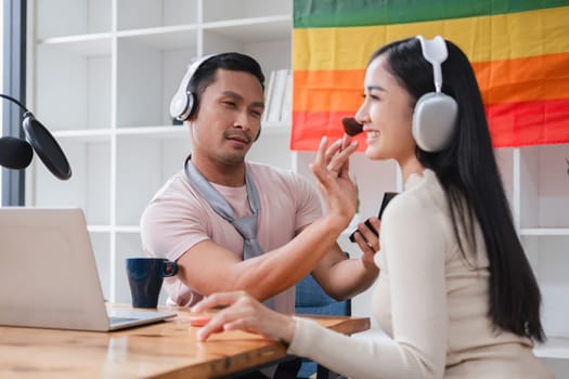 A young gay man and his girlfriend use a laptop and microphone to stream podcast audio at a studio talking about gender liberation..