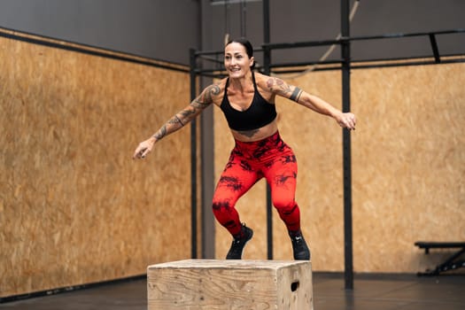 Motion photo of a mature strong woman jumping on box in a cross training gym