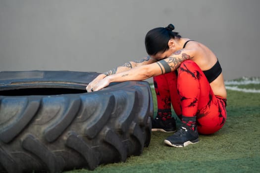 Tired mature sportive woman training with truck wheel in a cross training gym