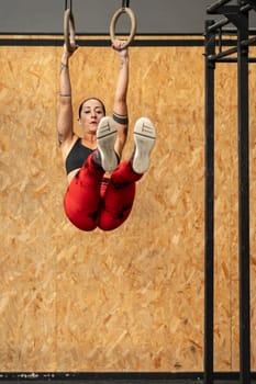Vertical photo with copy space of a mature sportive woman doing core exercises using Olympic ring in a gym