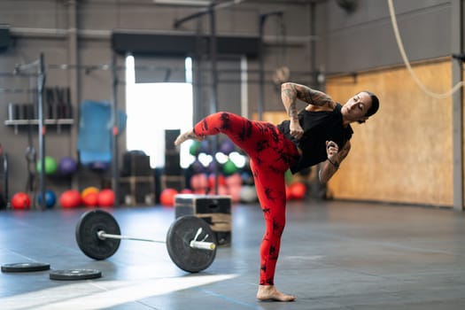 Mature sportive and strong woman working out kicking in a cross training gym