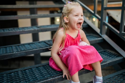 Child with hearing problem and cochlear implant dance in street, deaf kid began to hear. Hearing loss in childhood and treatment concept. Copy space and empty place for text.