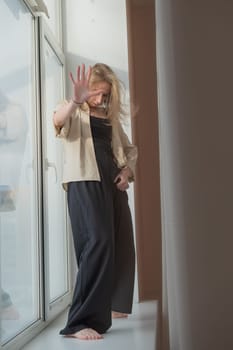 Caucasian woman dancing modern dance on the windowsill. Vertical photo