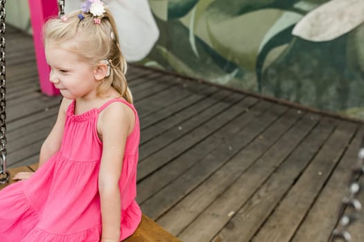 Child girl walks and have fun outdoor with cochlear implant on the head. Hearing aid and treatment concept. Copy space vertical.