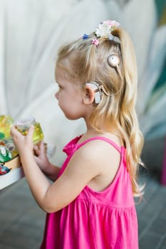 Child girl walks and have fun outdoor with cochlear implant on the head. Hearing aid and treatment concept. Copy space vertical.