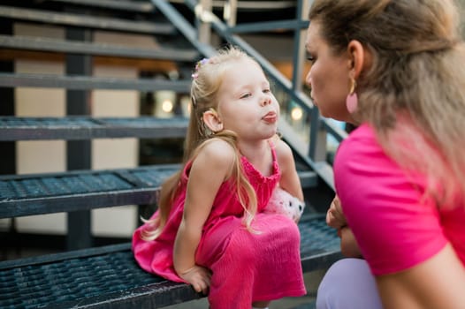 Deaf child with cochlear implant for hearing audio and aid for impairment having fun and laughs with mother outdoor in summer. Sound fitting device to help with communication listening and interaction.