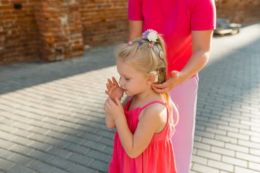 Child girl walks and have fun outdoor with cochlear implant on the head. Hearing aid and treatment concept. Copy space vertical.