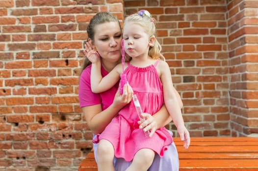 Child girl with cochlear implant with her mother spend time outdoor. Hear impairment and deaf community concept. Deaf and health concept. Diversity and inclusion. Copy space.