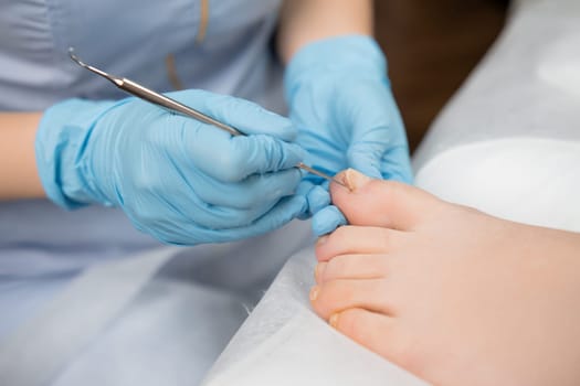 Woman feet receiving pedicure in beauty clinic.